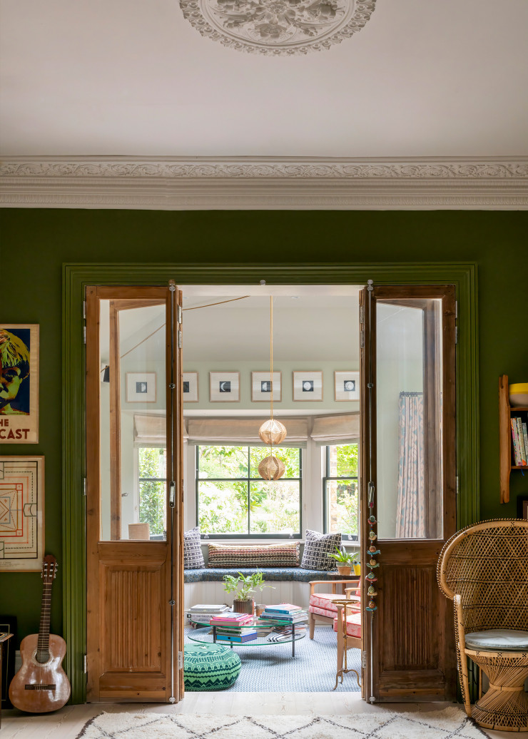 Les portes du salon de musique, dont les murs sont recouverts d’une peinture verte Bancha (Farrow & Ball), s’ouvrent sur un autre petit salon qui évoque un jardin d’hiver grâce au bow-window. Au-dessus des fenêtres, série de gravures « Phases of the Moon » de l’Adam Ellis Studio.
