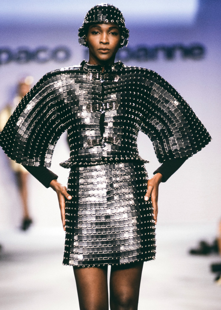 Ensemble veste et jupe de la collection « Haute couture automne-hiver 1990-1991 ». Plaques métalliques rectangulaires estampées « M », laquées noires (plaques fournies par le fabriquant Manulatex), fond en maille de fibres synthétiques côtelée noire.