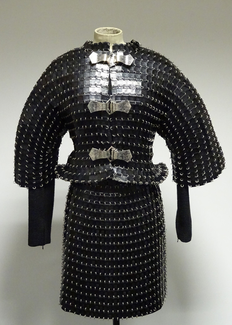 Ensemble veste et jupe, Collection haute couture Automne-Hiver 1990-1991, Plaques métalliques rectangulaires estampées « M » laquées noir (plaques fournies par le fabriquant Manulatex), fond en maille de fibres synthétiques côtelée noire, Paco Rabanne.