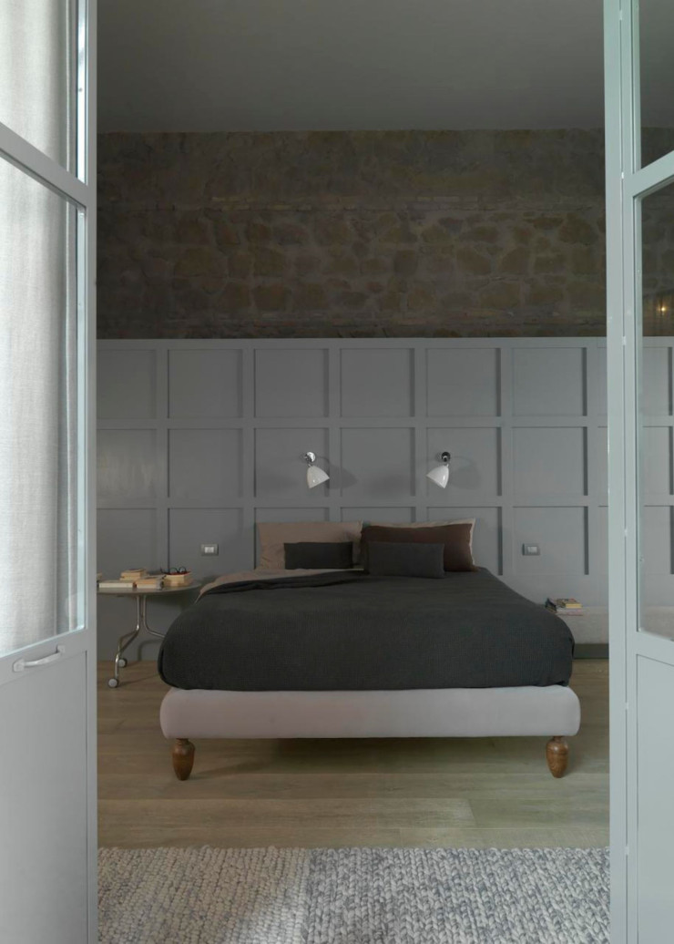 Dans la chambre principale, un dressing se niche derrière la tête de lit et s’étend tout le long du mur. Lit réalisé sur mesure par un artisan. Table d’appoint DePadova. Tapis Gan.