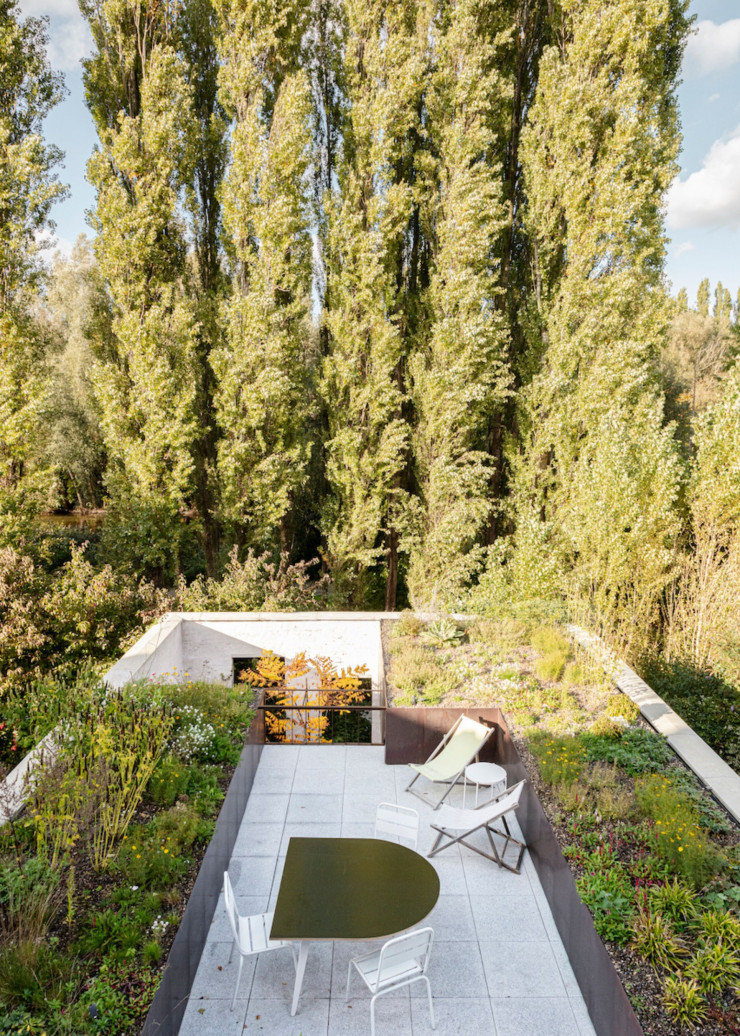 Le parc derrière la maison en cuivre s’impose comme un prolongement naturel de la terrasse. Table dessinée par l’architecte lui-même.