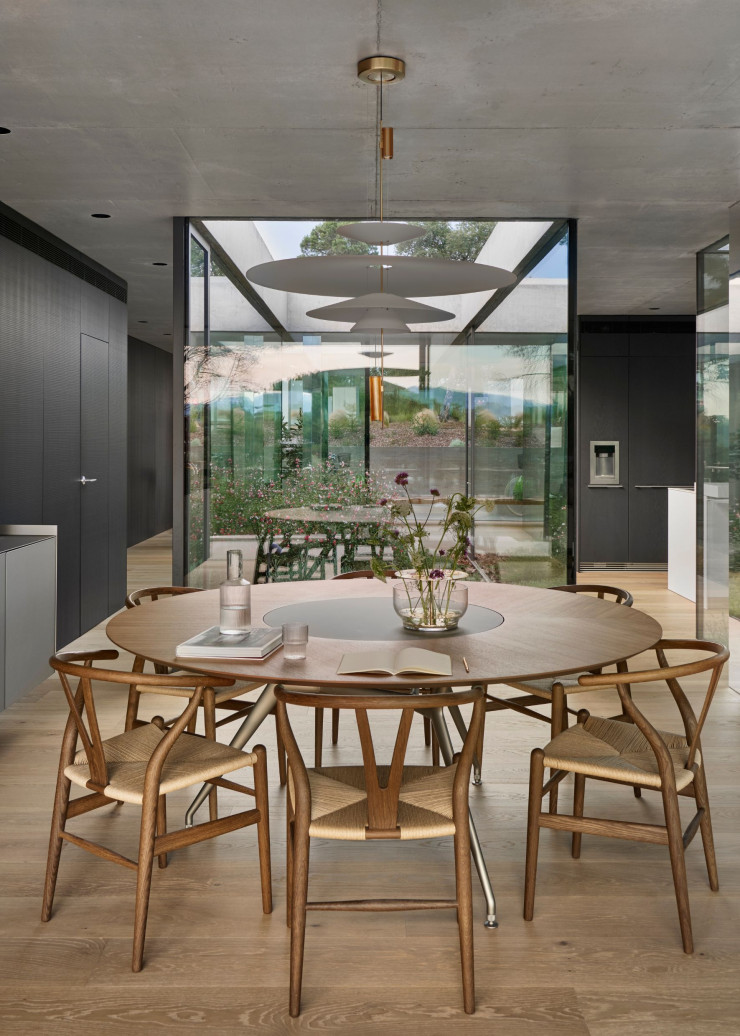 Dans le coin repas, la suspension Flamingo 1550, d’Antoni Arola (Vibia), en acier finition dorée et méthacrylate, se déploie au dessus d’une table ronde à double plateau en bois et en métal Manta (Rimadesio) et de chaises CH24 « Wishbone », design Hans J. Wegner (1949, Carl Hansen&Søn). Vase Ikebana, de Jaime Hayón (Fritz Hansen).