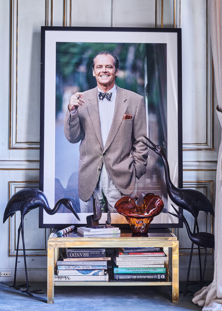 Un grand portrait de Jack Nicholson, l’ami éternel, pris en 1994 à Saint-Jean-Cap-Ferrat, où les deux copains passaient leurs vacances ensemble. Les trois oiseaux ont été rapportés de Kobe, au Japon, en 1948. Les sculptures des mains sont un souvenir d’Inde, sur une table basse Flaminia, l’une des premières lignes dessinées par Willy Rizzo, en 1968. Vase Water Illusion, fabriqué à la main, en verre coulé recyclé, design Assia Karaguiozova (Poltrona Frau).