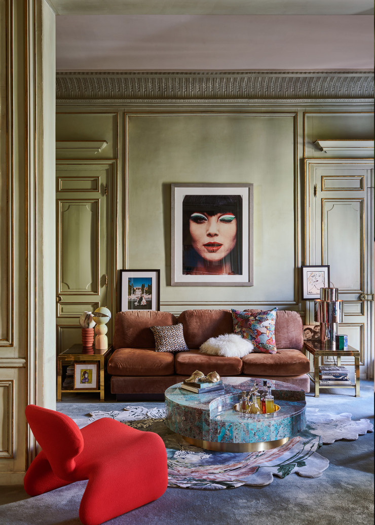 Le petit salon de l’appartement de Willy et Dominique Rizzo à Paris, entièrement meublé par les soins du designer. Un grand portrait pop de son ancienne compagne l’actrice Elsa Martinelli en Italie, en 1969, domine l’ensemble. À gauche, au-dessus du canapé C recouvert de sanglier, une vue de Rome dans les années 60. La réinterprétation en amazonite de la table tournante TRG, initialement créée à la fin des sixties, a été présentée au PAD, à Paris, cette année. Fauteuil Djinn, design Olivier Mourgue (Airborne). Sur le canapé, respectivement à gauche et à droite, housses de coussin Leo en lin et en coton, et Jungle Birds, en viscose et en polyester, entièrement en tapisserie à l’ancienne (Madura). Au milieu, coussin Mil en suédine, en peau et en poils d’agneau de Mongolie (Ligne Roset).