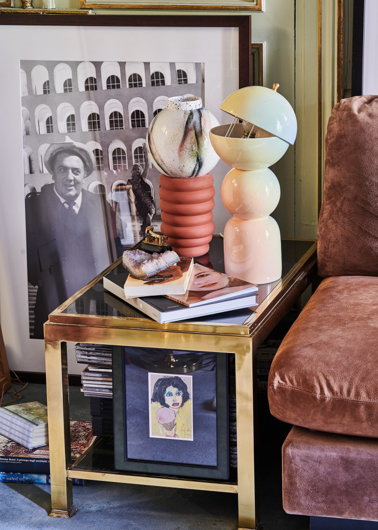 Près du canapé C, table basse Flaminia en laiton poli et en marbre noir, les deux signés Willy Rizzo. Parmi les souvenirs, Dominique Rizzo peinte par Jack Nicholson, un livre sur l’œuvre du photographe avec son portrait de Marilyn Monroe en couverture et, derrière, un tirage représentant le réalisateur Federico Fellini et l’actrice Anita Ekberg à Cinecittà, en 1960, l’année du film La Dolce Vita. Bougeoir rose en céramique avec sphère en faïence peinte et émaillée à la main. Luminaire dégradé de couleurs pastel en céramique, collection « Spacetrip » (Villa Arev).