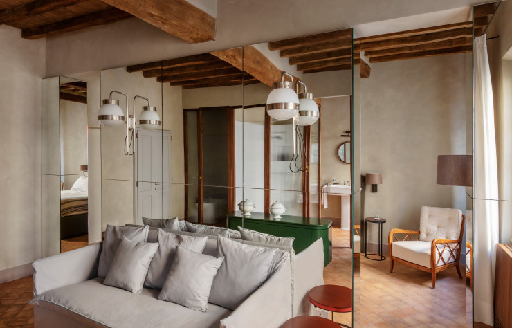 Dans la suite, Eligo Studio a conçu une armoire recouverte de miroirs, qui sépare la chambre du salon. Applique Delta, années 60, de Sergio Mazza (Artemide). Canapé Ghost de Paola Navone (Gervasoni 1882). Fauteuil vintage signé Paolo Buffa.