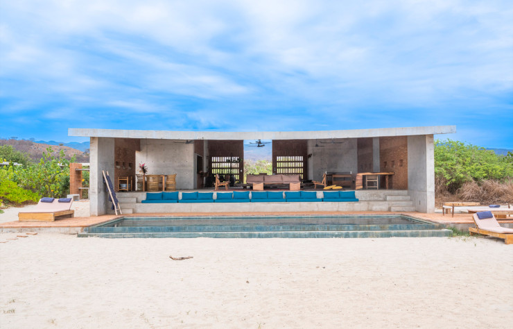 Dans le voisinage immédiat de la Fundación Casa Wabi, l’artiste Bosco Sodi a fait construire plusieurs autres lieux d’hébergement disponibles à la location, parmi lesquels Casa Cons. Son architecture très minimaliste se présente sous la forme d’un immense préau ouvert sur la plage, recouvert d’une toiture également en béton. Ce grand volume accueille à la fois la salle à manger, le salon, la cuisine ouverte… tandis que les chambres sont réparties dans cinq pavillons construits sur l’arrière du module principal.