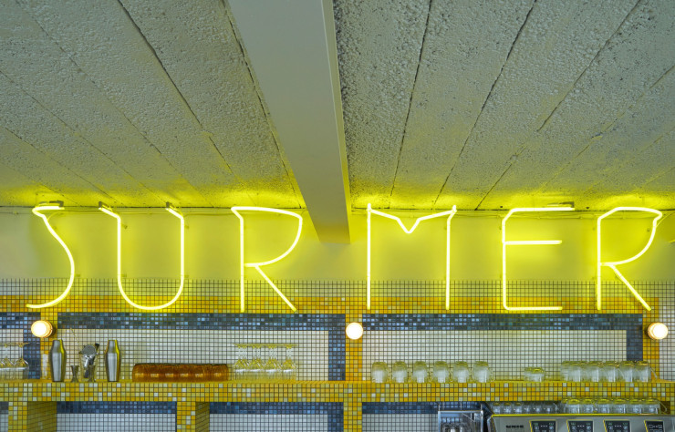 Une immense enseigne au néon « suspendue » au-dessus d’un comptoir recouvert de carreaux de céramique bleus, blancs et jaunes vient donner un coup de peps à ce néo-resto de plage.
