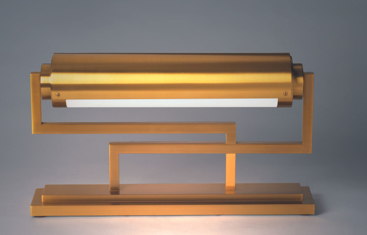 Le modèle 234, ici en finition dorée, est la matérialisation d’un nouveau concept d’éclairage de bureau pensé par Jean Perzel. Le cylindre de verre optique dépoli est cerclé d’un cache pivotant permettant une orientation plus précise de la lumière.
