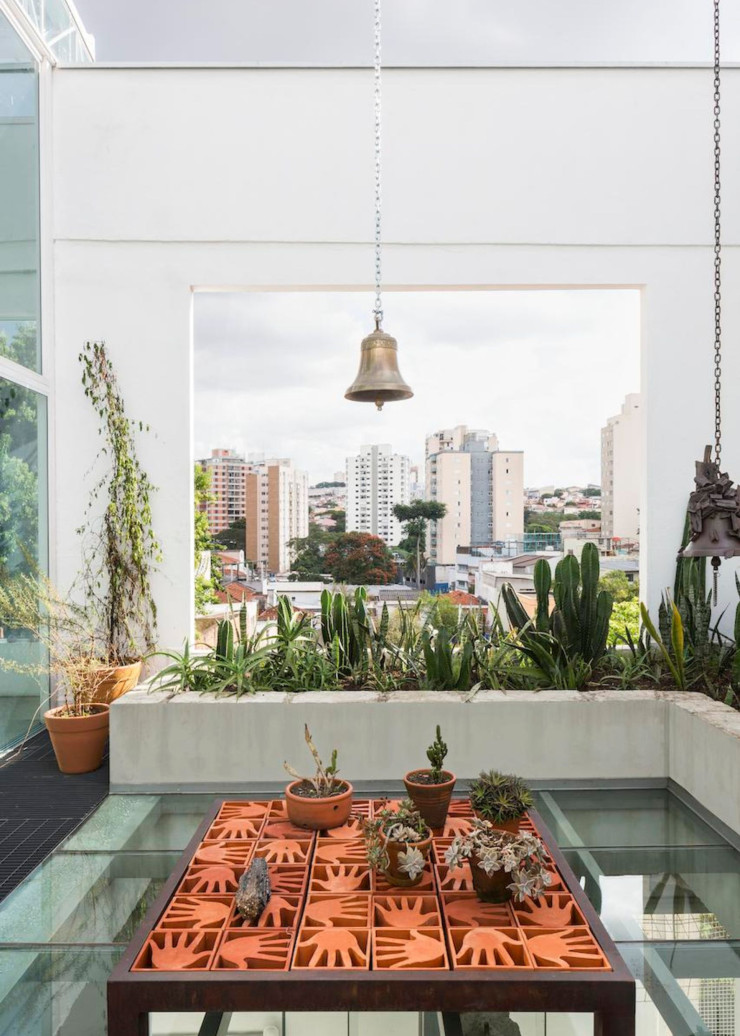 Sur la terrasse du nouveau studio Campana, la cloche est à la fois un clin d’œil au patronyme des deux frères designers et un objet attestant du regard plus spirituel que Humberto pose aujourd’hui naturellement autour de lui. Au premier plan, une table en briques ajourées, ou cobogós, en forme de mains tendues, conçues en réponse au désastre de la coulée de boues toxiques dans le Minas Gerais, en 2015.
