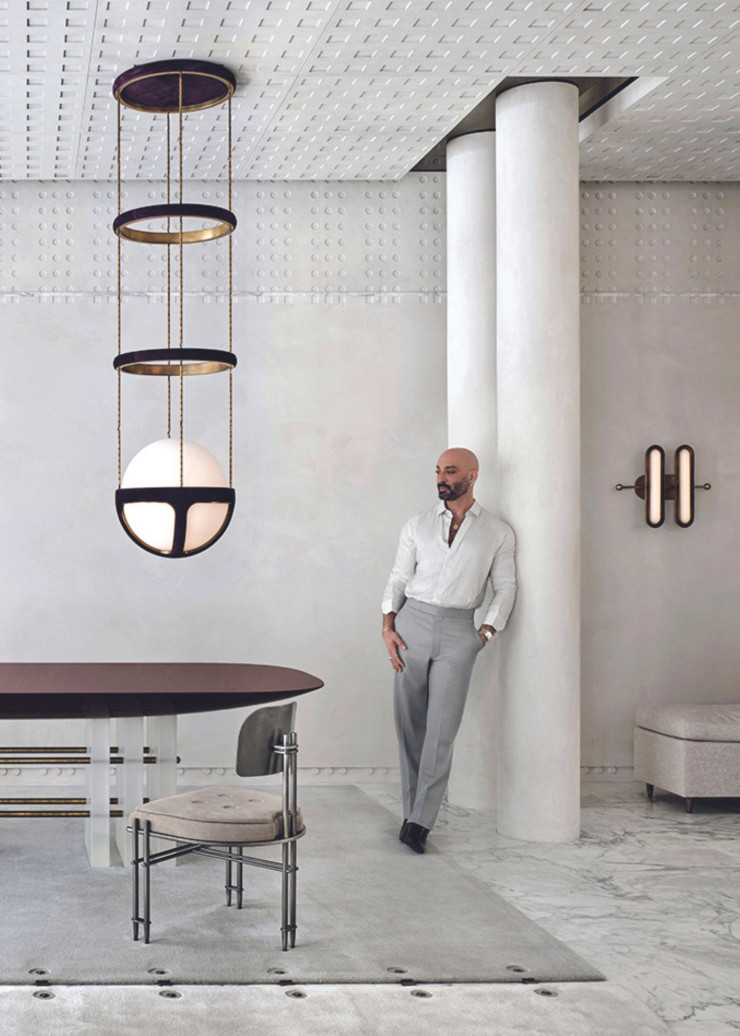 La galerie principale, au sol de marbre blanc Calacatta Classico, est ponctuée de colonnes. Table Segment, chaise Episode, suspension Reprise, tapis Sequence, applique Surface.