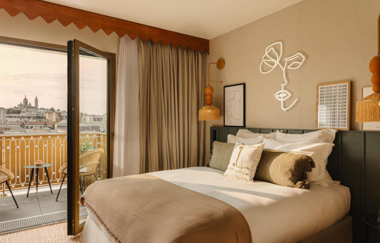 Les chambres arborent des tons chauds et une décoration aux accents poétiques. Ici, la chambre bénéficie d’un balcon avec vue sur la basilique du Sacré-Cœur.