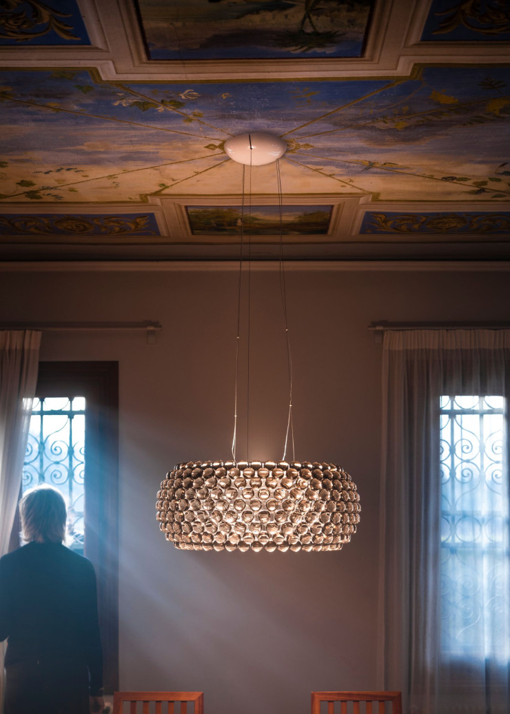 La suspension Caboche Plus, une déclinaison du modèle imaginé par Patricia Urquiola et Eliana Gerotto en 2005. Le corps de la lampe, en forme d’anneau, est composé de sphères en verre acrylique transparent ou fumé.