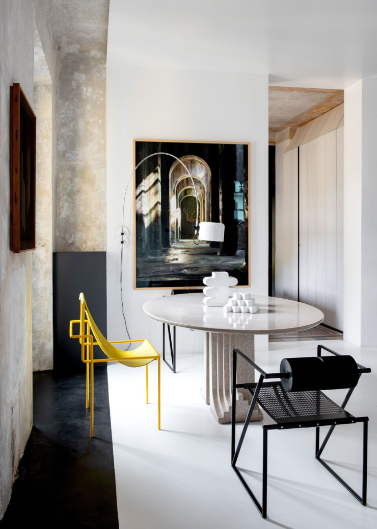 Au fond, dans l’entrée, table vintage, vase noir Paola C. et bol de Josef Hoffmann (Bieffeplast). Applique, design Sergio Mazza (Artemide). Photo de Tobias Zielony, galerie Lia Rumma, à Naples. Au premier plan, table ovale en granit Samo, design Carlo Scarpa (1971, Simon Gavina). Céramiques blanches des sixties. À gauche, chaise des années 80 Seconda, design Mario Botta (Alias). Chaise jaune, prototype. Chaise ultralégère en fil d’acier, design Alberto Colzani (Baleri Italia). Luminaire de la collection « Coupé », design Joe Colombo (Oluce). Au mur, entre les deux fenêtres, œuvre des années 70 signée Xanti Schawinsky. Lit de jour Berlin, de Bruno Mathsson. Lampadaires Pascal, design Vico Magistretti (Oluce). Tables basses Cappellini. Verre rouge et noir, design Ettore Sottsass (Venini).