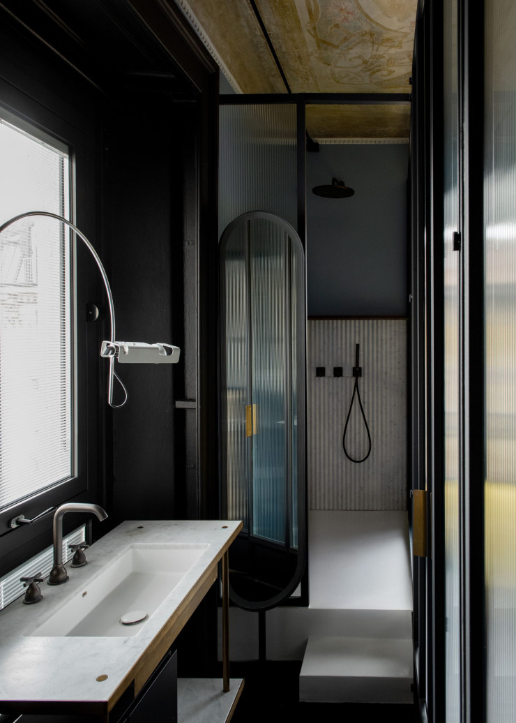 Lavabo intégré dans une table faite sur mesure en laiton bruni et en marbre. Robinetterie Agape. Lampe Spider, design Joe Colombo (Oluce). Panneaux muraux de douche en marbre de Carrare plissé.