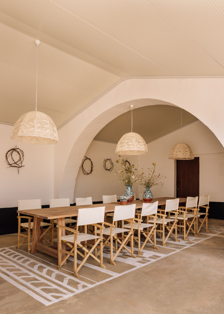 Dans la salle à manger ouverte sur la cour, table en bois fabriquée sur mesure, vases et coupe à fruits en céramique faits main. Les luminaires aux abat-jour délicatement brodés et le tapis peint au sol apportent une note poétique.
