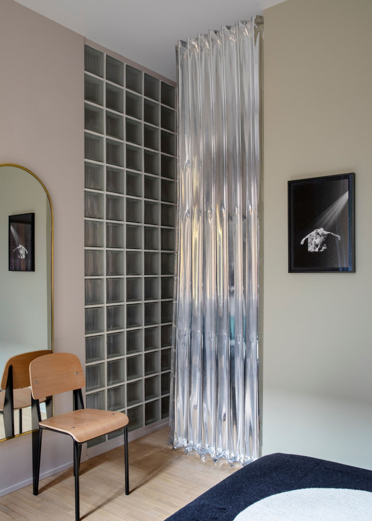 Dans la chambre parentale, le mur de briques de verre et le rideau effet miroir Dooor, qui abrite le dressing, apportent une touche contemporaine. Chaise Standard, design Jean Prouvé (Vitra).