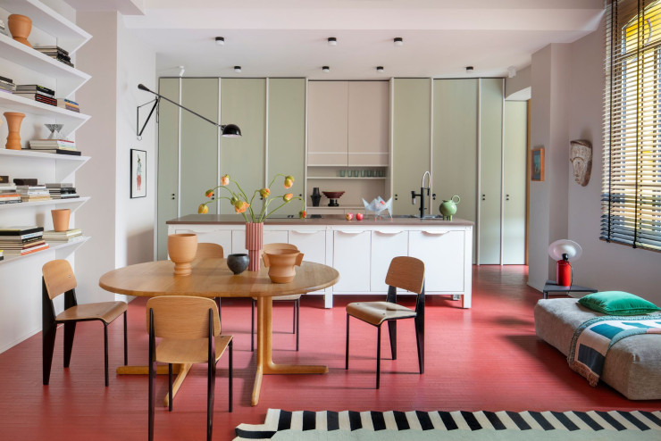 Dans la cuisine-salle à manger, sur la table vintage chinée par le studio Sagaría, céramiques de Damiano Groppi et vase collection « Le Torri », de Francesca Verardo (Spazio Mari). Chaises Standard, de Jean Prouvé (Vitra). Applique 265 de Paolo Rizzatto (Flos). Posés sur l’îlot conçu par Very Simple Kitchen, coupe à fruits 540, d’Ettore Sottsass (Bitossi Ceramiche), et vase signé Damiano Groppi. En arrière-plan, façades sur mesure recouvertes de résine Microresina (Kerakoll) dissimulant les rangements. À côté, au mur, œuvre de Rachel Liebeskind. Le parquet en bois est enduit d’une résine Microresina (le tout, Kerakoll).