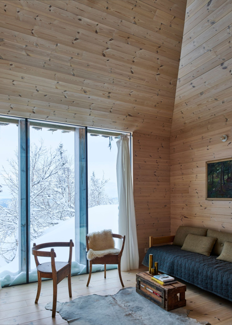 Côté salon, en plus de son mobilier typique des pays du Nord, l’aménagement intérieur, avec ses grandes baies vitrées, fait aussi référence au mode de vie californien, où le couple a vécu. Fauteuils et tableau chinés sur des marchés aux puces d’Oslo, canapé Arbour et couvre-lit Mega Dot (Hay).