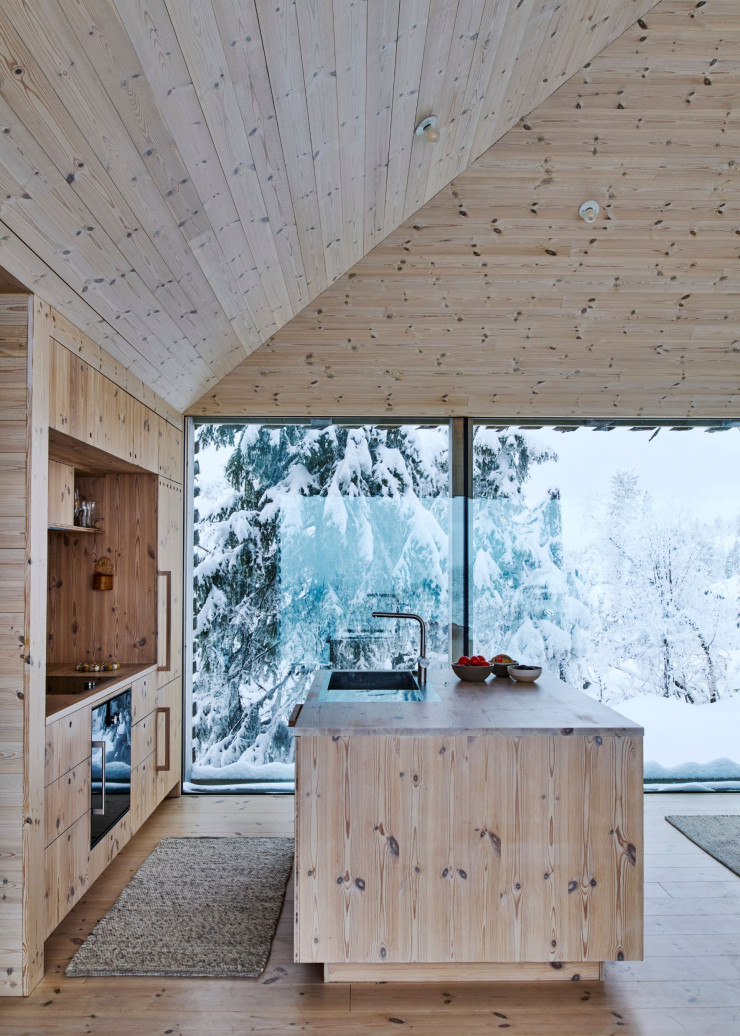 La cuisine ouverte et son îlot central sont habillés de pin noueux, à l’instar de l’ensemble du chalet.